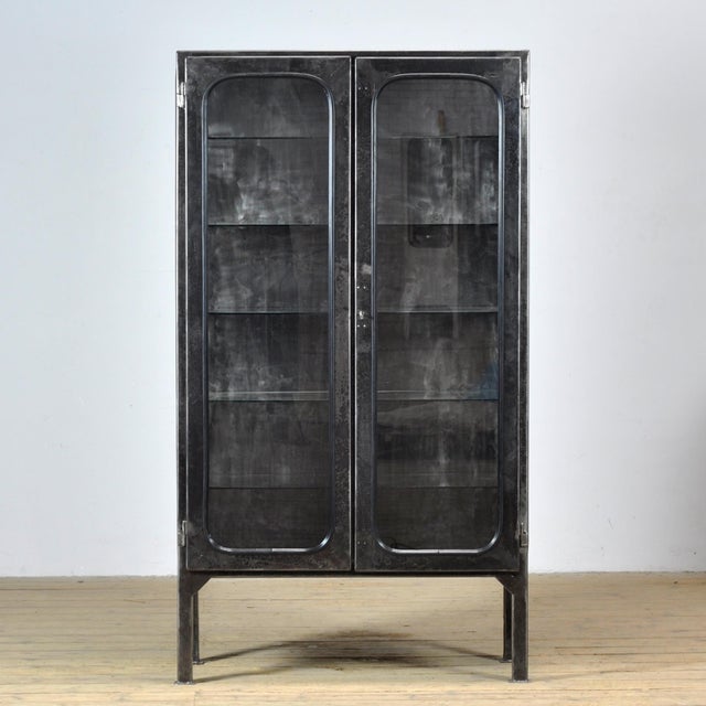 Vintage medicine cabinet from the 1970s, produced in Hungary. The cabinet is made of iron and glass, with the glass held...