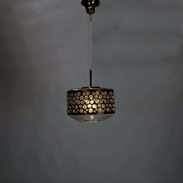 This beautiful pendant lamp, designed by Rupert Nikoll in the 1960s, consists of a brass lampshade with several round...