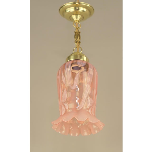 Rose-coloured Art Nouveau shade with floral pattern, 1910s The surface of the brass holder is polished. The lamp gives a...