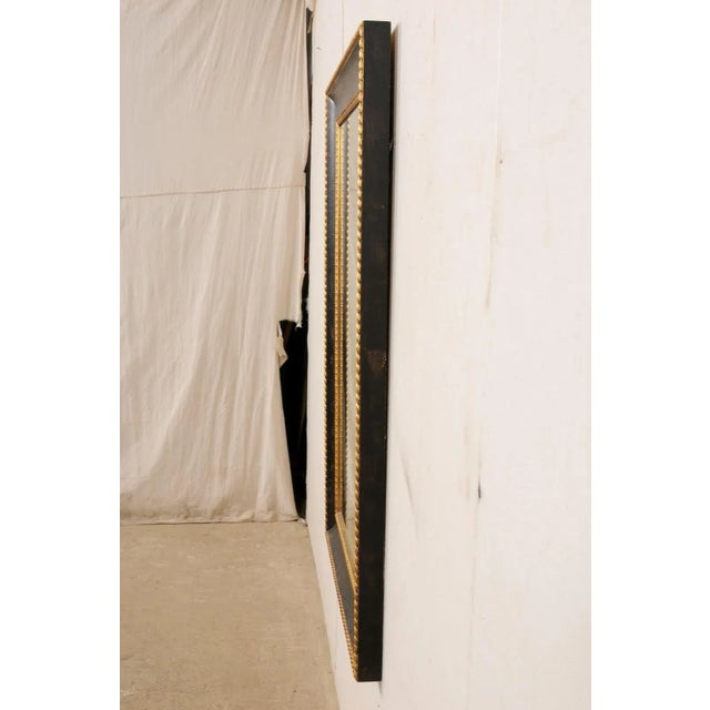A vintage American carved and painted wood mirror. This rectangular-shaped mirror has a black wood frame, which has been...