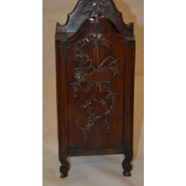 Late 19th century salt box, with an intricate carved flower motif on the sliding door, resting on scroll feet with a top...