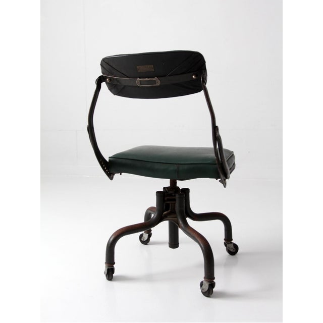 This vintage DoMore swivel office chair features an industrial steel frame, rolling casters, and an adjustable backrest...