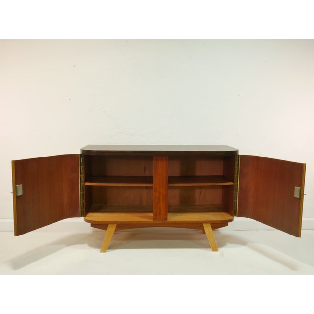 This sideboard is an original piece from the 1960s and impresses with its harmonious design and the warm contrast of light...
