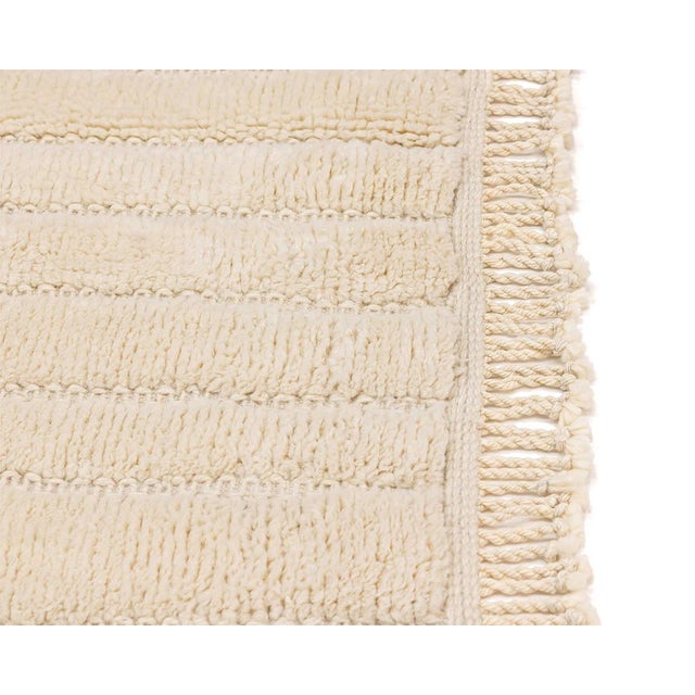 Quiet architecture in wool: pure ivory, shaped by texture alone. A calm ivory field covers the rug from end to end, soft...