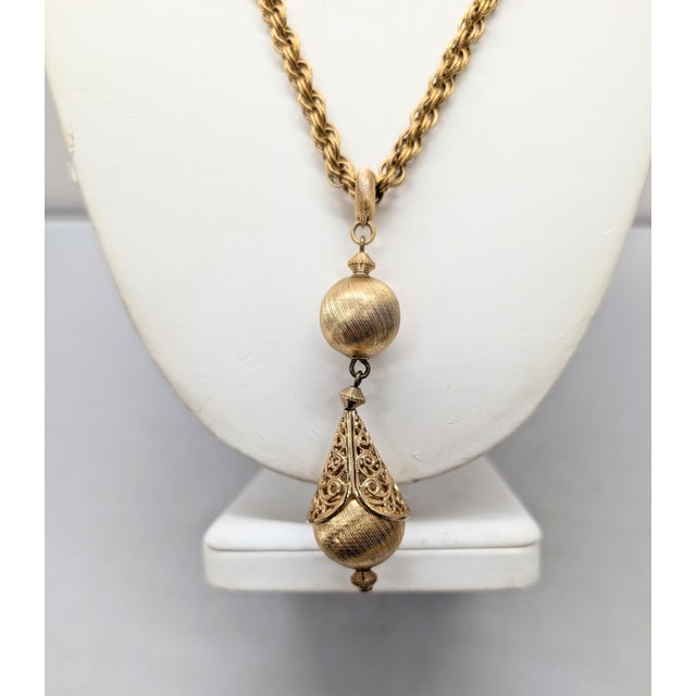 Goldtone textured round drop with conical filigree top with a textured rhodium ball above single pendant drop necklace...