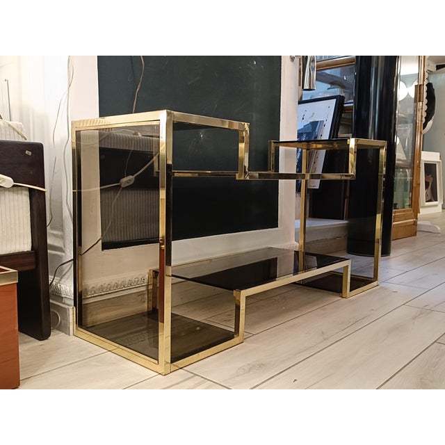 Brass étagère with smoked glass shelves. This piece stands out for its unique and sophisticated geometric design,...