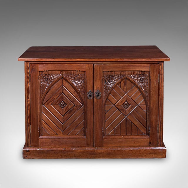 This is an antique Gothic Revival side cabinet. An English, pitch pine his & hers storage cupboard or bookcase, dating to...