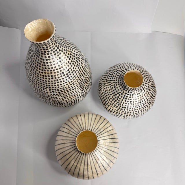 A beautifully curated set of three capiz shell vases featuring complementary silhouettes and graphic patterns. The...