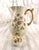 This is a white Jean Pouyat Limoges Chocolate pot. The right side has purple hand painted flowers with green leaves. One...