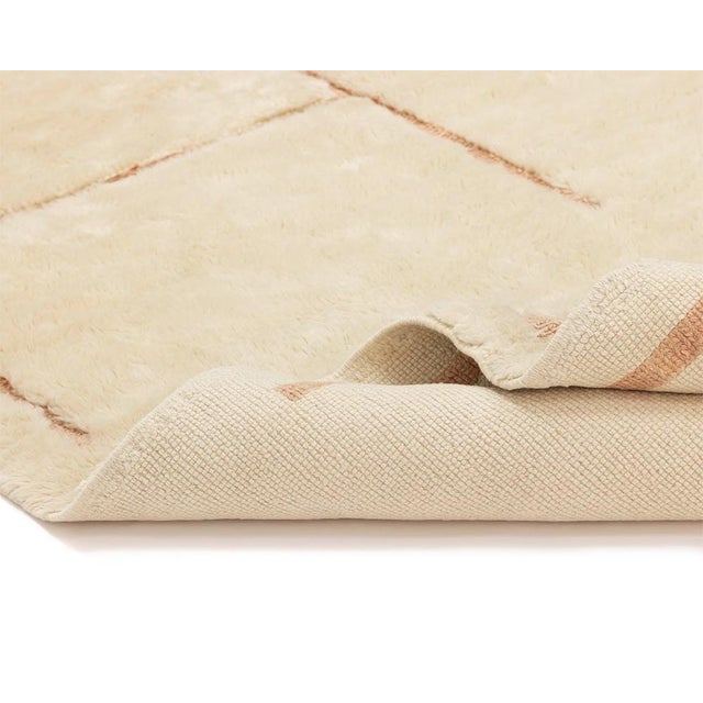 Elegant hand-knotted wool rug in a delicate Ivory hue, accented with subtle Tender Peach geometric lines, crafted to...