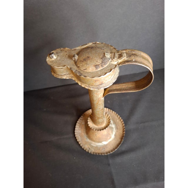 An extraordinary, highly architectural 19th-century sheet tin "Betty" grease lamp permanently integrated into a weighted...