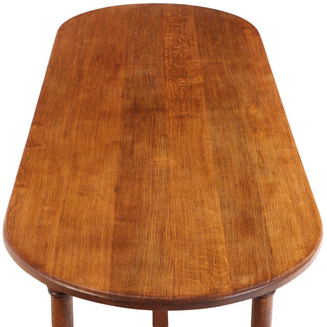 An unusual mid-century French oak table, circa 1950, featuring a long oblong top with gracefully rounded ends. The...
