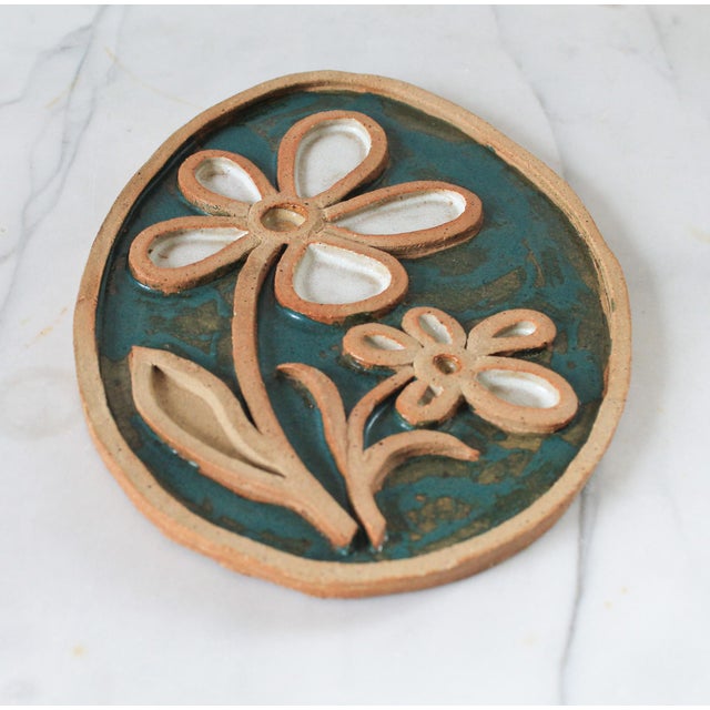Vintage studio art pottery trivet with floral motif. Signed by artist "Alve". Dated 1975. Minor age wear. No chips.