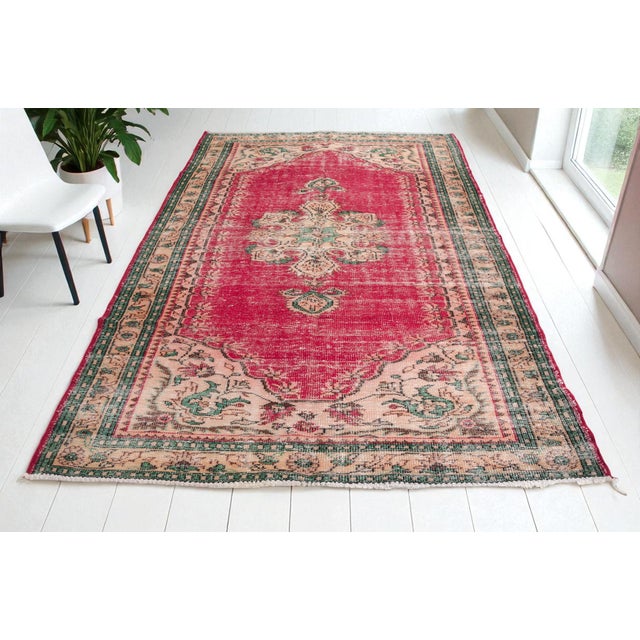 This is a vintage Turkish Oushak rug from the Mid 20th Century. The piece was hand-knotted.