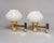A pair of understated gold-coloured wall lamps with polished metal bodies, slightly upwards-tilted stems, flared rims and...