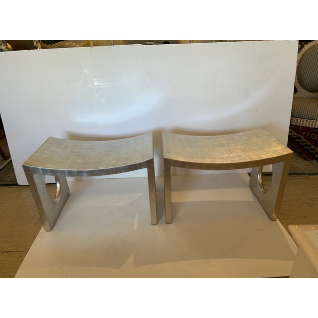 Chic stylish contemporary pair of silverleaf lacquered benches having oval cutouts on the sides and sculptural curved seat...