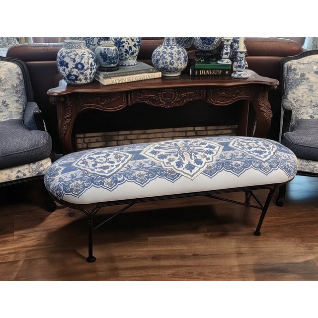 Custom upholstered chinoiserie-style bench featuring dramatic blue and white porcelain-inspired textile upholstery on a...