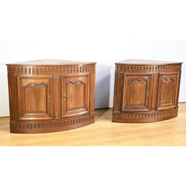Pair of large identical property corners in walnut. Each corner, arched in shape on the facade, opens with two dark doors...