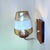 A vintage mid-century wall sconce featuring a warm amber and clear glass shade with a distinctive geometric etched or...