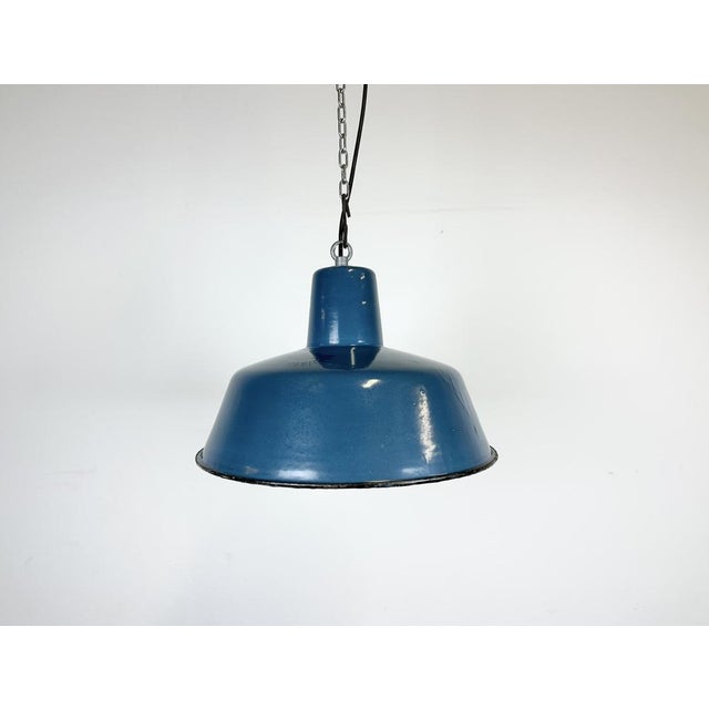 Industrial blue enamel pendant light made in Poland during the 1960s. White enamel inside the shade. Iron top. The...