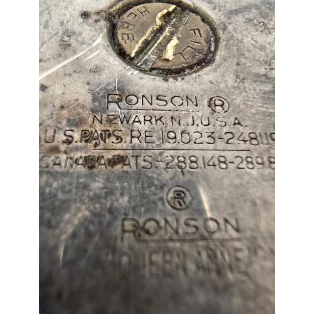A vintage Ronson "Queen Anne" silver-plated table lighter featuring a classic pedestal form adorned with decorative...