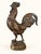 A proud Gallic rooster, immortalized in bronze, head held high, wings slightly spread, tail falling in a generous plume....
