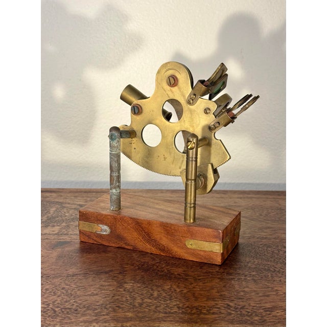 A handsome antique brass nautical sextant mounted on a custom hardwood display stand, offering the timeless appeal of...