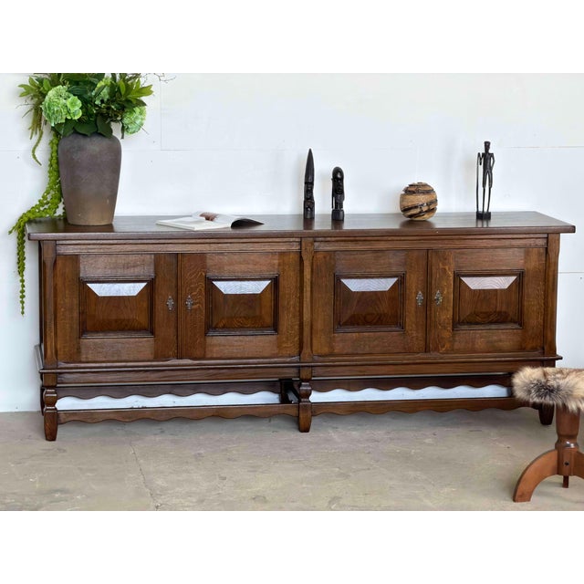 Danish sideboard in stained solid oak, by Henning Kjærnulf, 1960s. The case is fitted with four doors, each set with a...