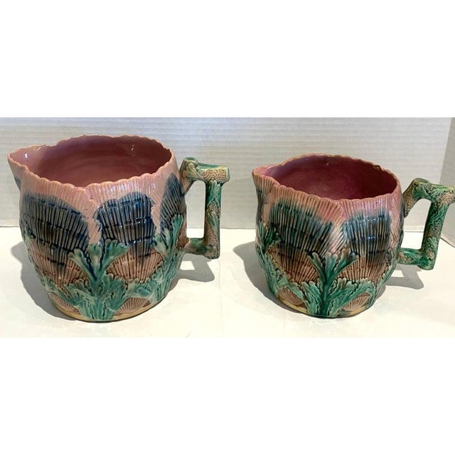 A collection of six Etruscan Majolica shell and seaweed pitchers, five in the typical shell and sea weed pattern, one in a...