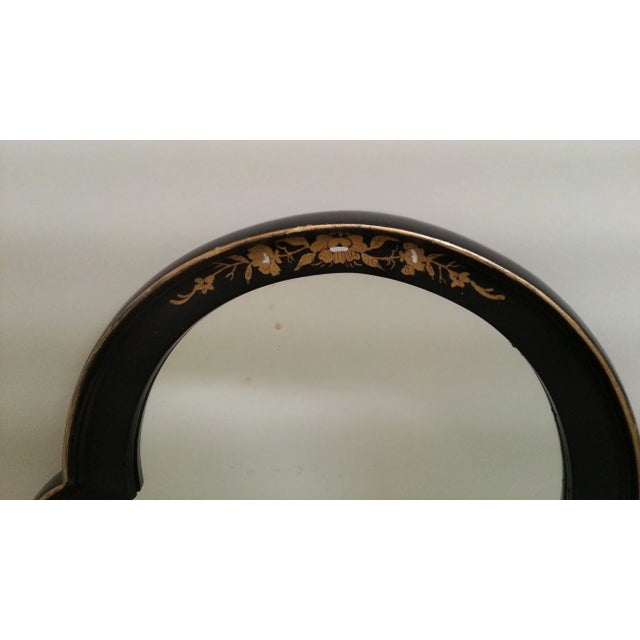 Black lacquer mirror with gold pin striped border and gilt decoration.
