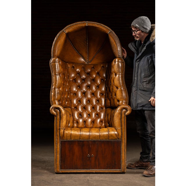 Oversized high-back Porter's Chair upholstered in rich brown leather, featuring deep diamond tufting across the back,...