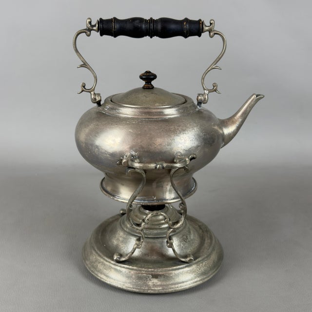 An elegant vintage tea set with a tilting teapot on a stand and a built-in burner, attributed to 20th-century manufacture....