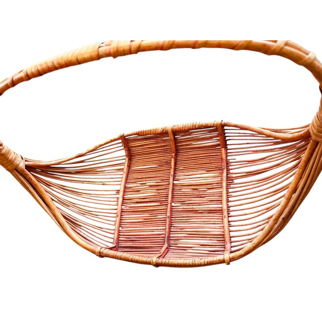 Mid 20th century Asian lightweight handwoven basket featuring an elongated oval form and wrapped handle. Traditionally...