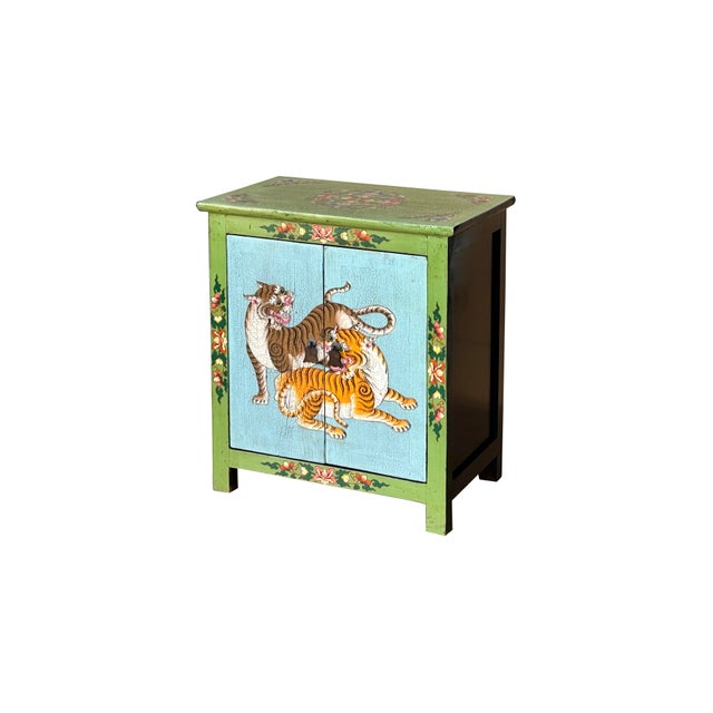 This striking, hand-painted wooden cabinet features a vibrant folk-art aesthetic, characterized by a bold palette of lime...