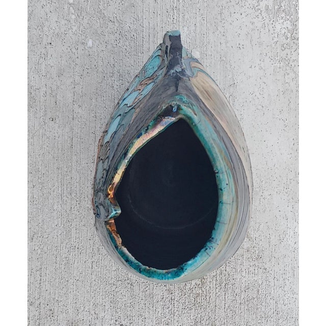 A colorful and meticulously designed stoneware pottery vase glazed in a raku technique that gives off a metallic sheen....