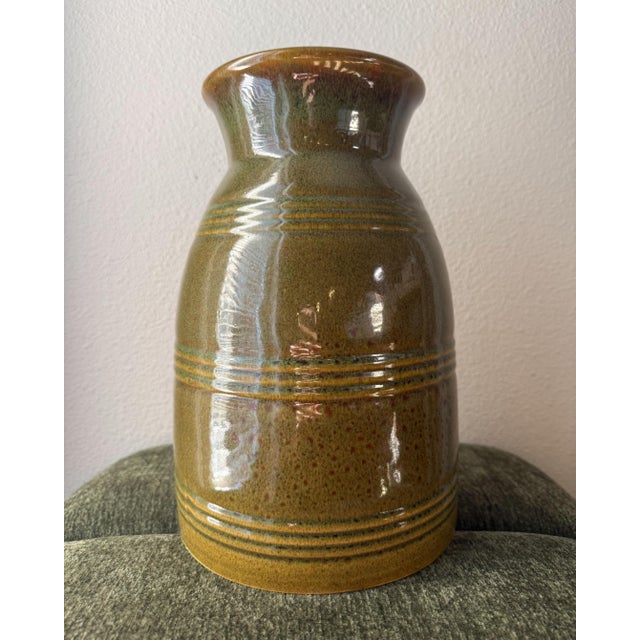 Artist-signed glazed pottery vase featuring an olive green and brown reactive glaze with subtle ochre and blue-green...