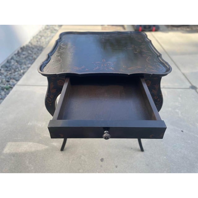 Black pavilion side table with drawer. Japanned finish with cabriole legs and scalloped top. There are gold floral designs...