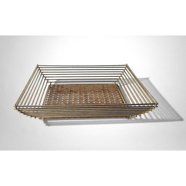 An elegant and refined basket featuring a structure composed of lacquered brass slats that frame a clear lucite panel,...