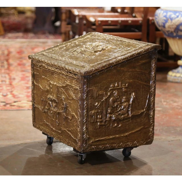 Crafted in France, circa 1920, the antique wood and brass fireplace wood coffer stands on coasters; the trunk is decorated...