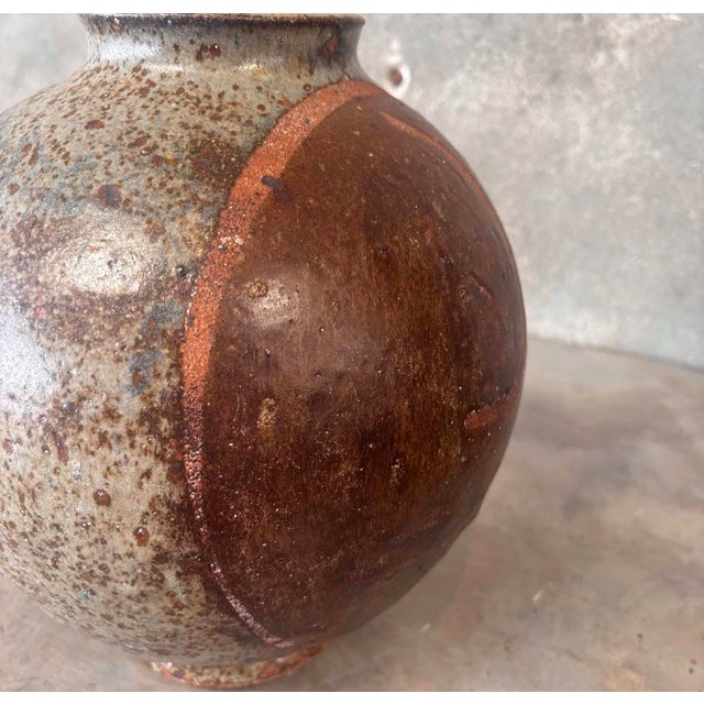 Vintage glazed ceramic tsubo-style vessel featuring a rounded sculptural form and richly textured earthy brown glaze. An...