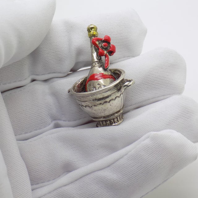 This vintage silver decorative object depicts an ice bucket with a champagne bottle miniature, crafted as a vitrine...
