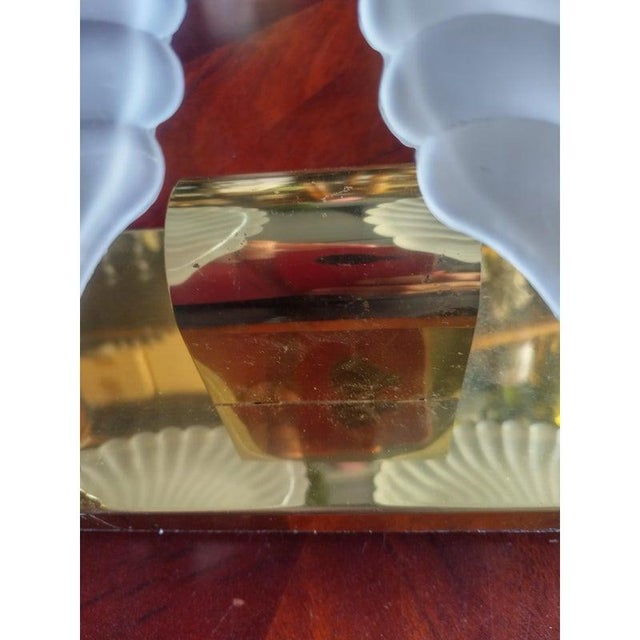 A vintage 2 light glass clamshell bathroom vanity light fixture. The fixture holds 2 bulbs, one on each side behind the...