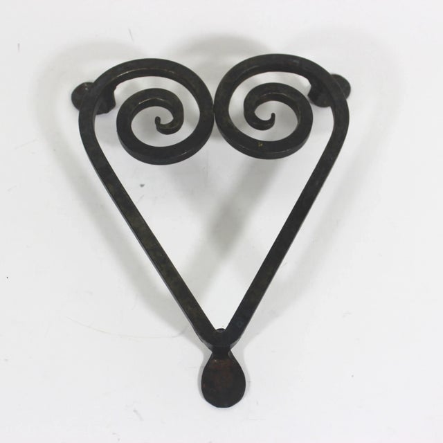 This rustic antique wrought iron trivet is gorgeous! It has been forged into a heart shape with three traditional penny...