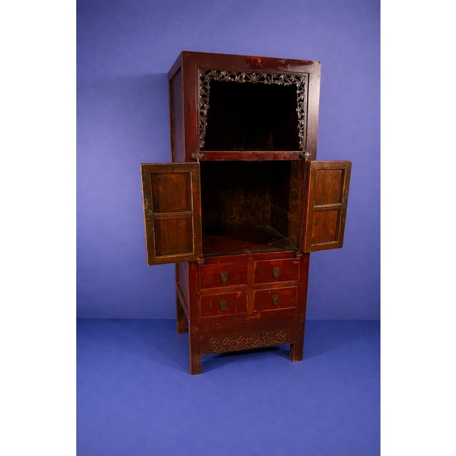 Chinese scholar's cabinet with carved floral design around the top shelf. Includes four drawers, storage space without...