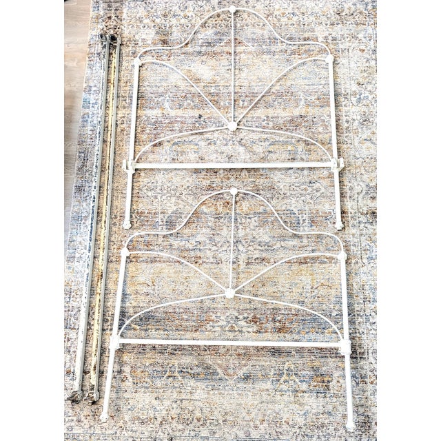 This Victorian-style antique twin bed frame has an ornate scalloped silhouette and central sunburst or fan-shaped...