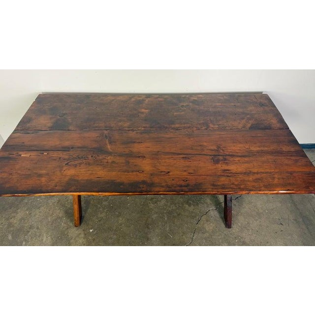 A beautifully worn, handcrafted trestle dining table with timeless rustic appeal, dating to the mid-20th century. The...