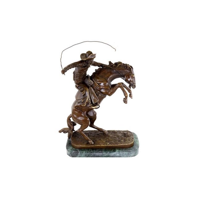 Western bronze sculpture depicting a cowboy mastering a rearing horse, inspired by Frederic Remington. The scene shows a...
