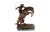 Western bronze sculpture depicting a cowboy mastering a rearing horse, inspired by Frederic Remington. The scene shows a...