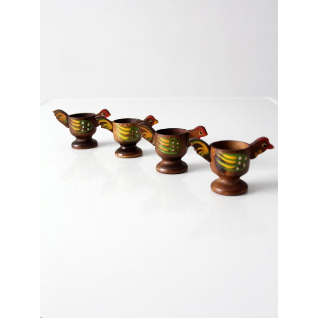 A charming set of four vintage wooden egg cups, each carved in the form of a small bird with hand-painted details in warm...