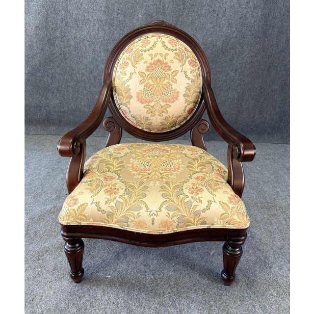 This elegant fauteuil features a carved wooden frame with gracefully scrolled arms, turned tapered legs, and a rounded...